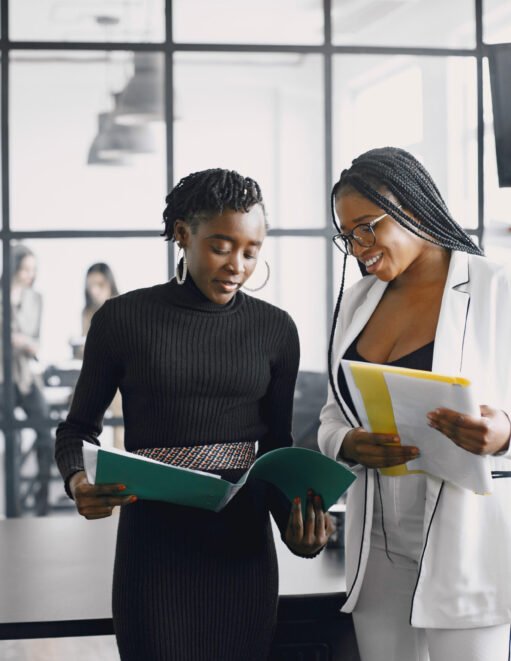 Business women talking near the desk during a coffee break in the hallway of the big corporation